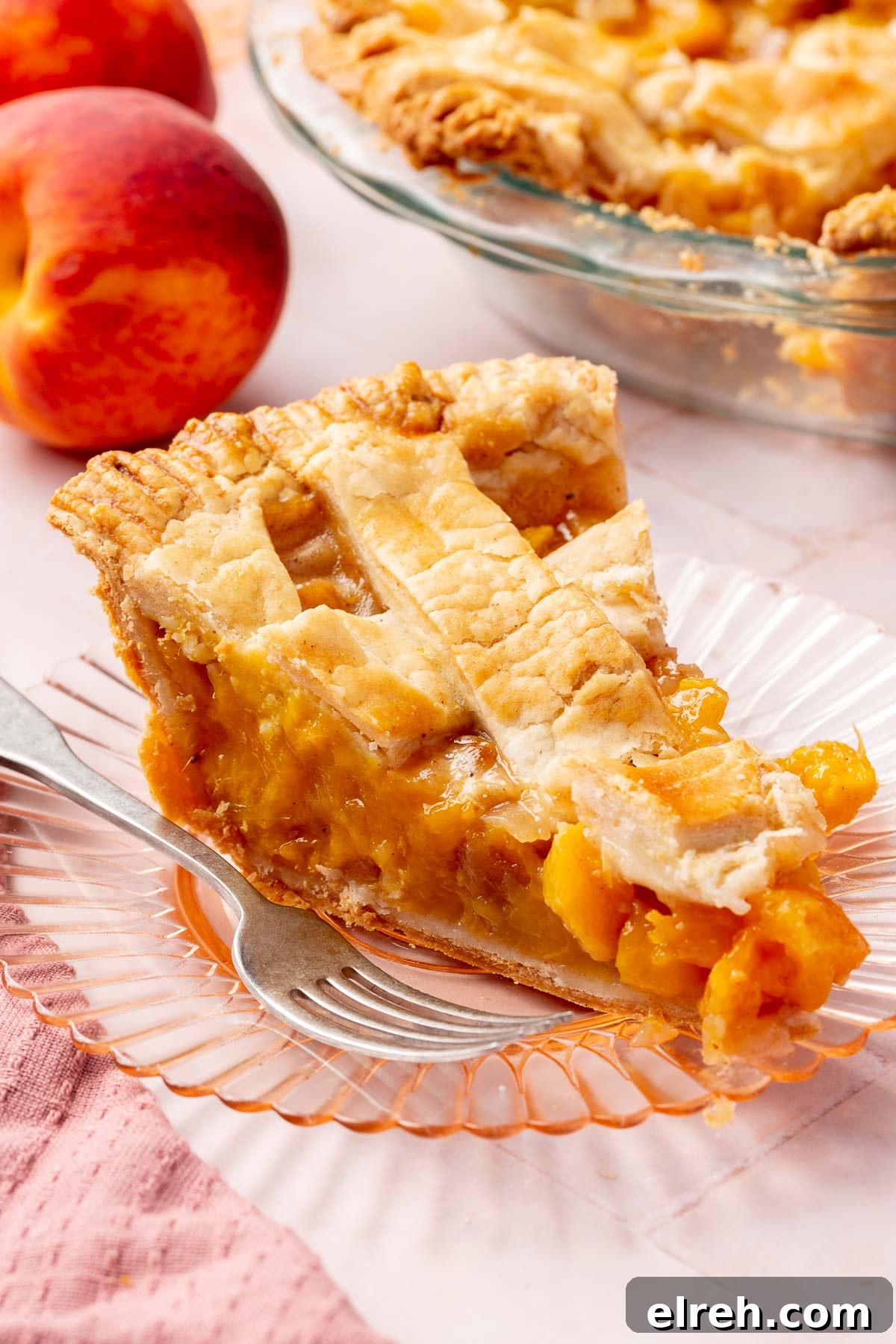 Gluten-Free Peach Mango Pie Recipe 4 A single slice of gluten-free peach mango pie on a dessert plate with more pie and peaches in the background.