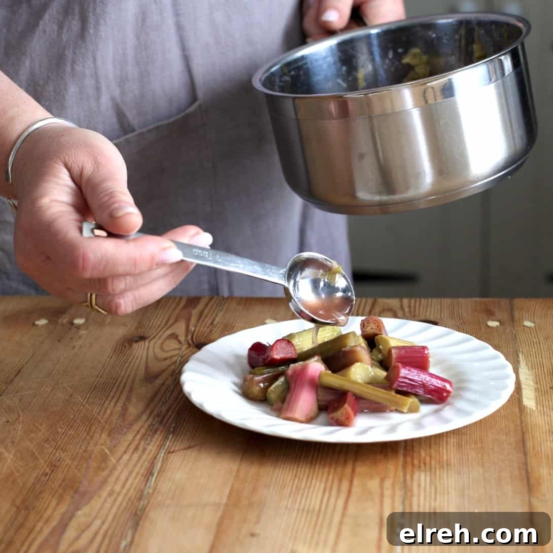 Woman spooning rhubarb juice from a silver saucepan onto a white plate of poached rhubarb