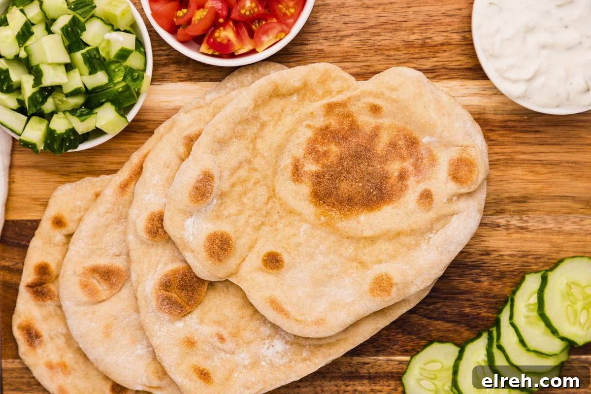 top view of pita breads on wooden board with veggies around.