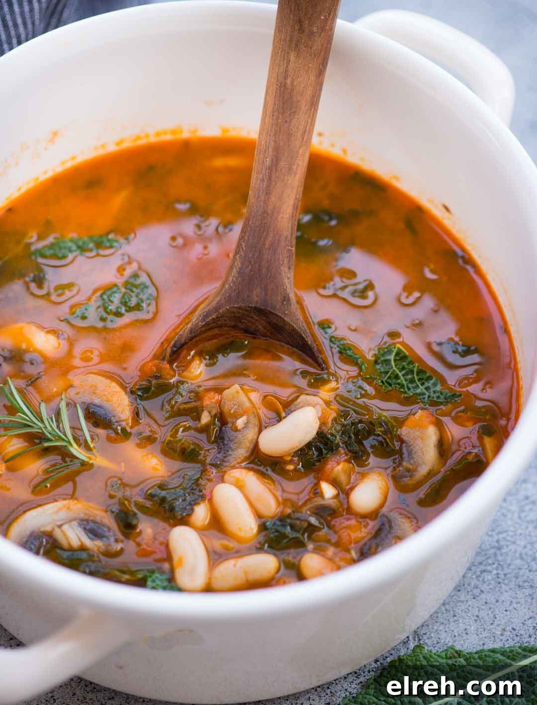 Bowl of white bean soup with mushroom and kale