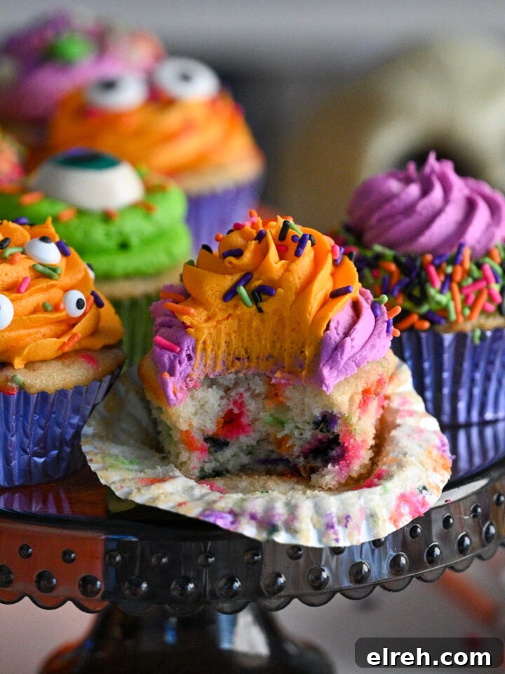 Close-up of colorful Halloween confetti cupcakes in foil cupcake liners, topped with orange, purple, and green frosting.