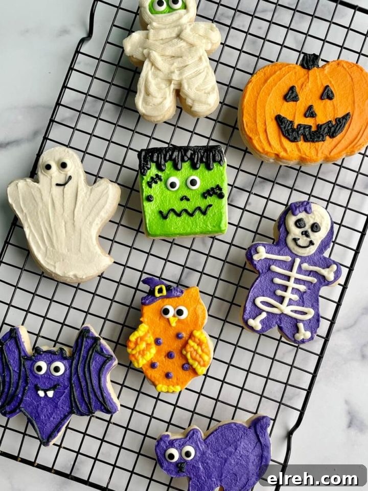 Several Halloween buttercream decorated sugar cookies on a cooling rack